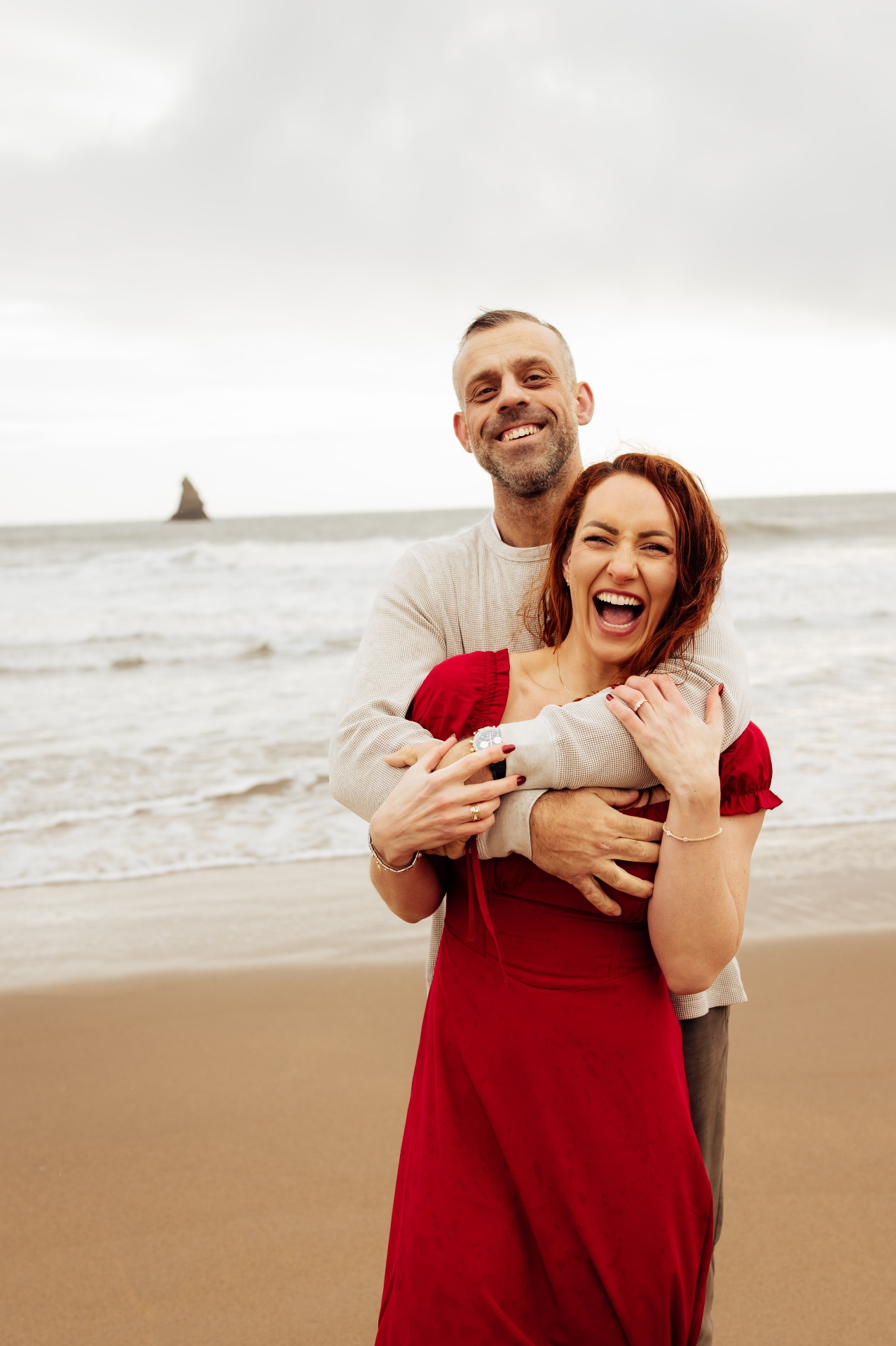 Marc and Emma laughing together on the beach